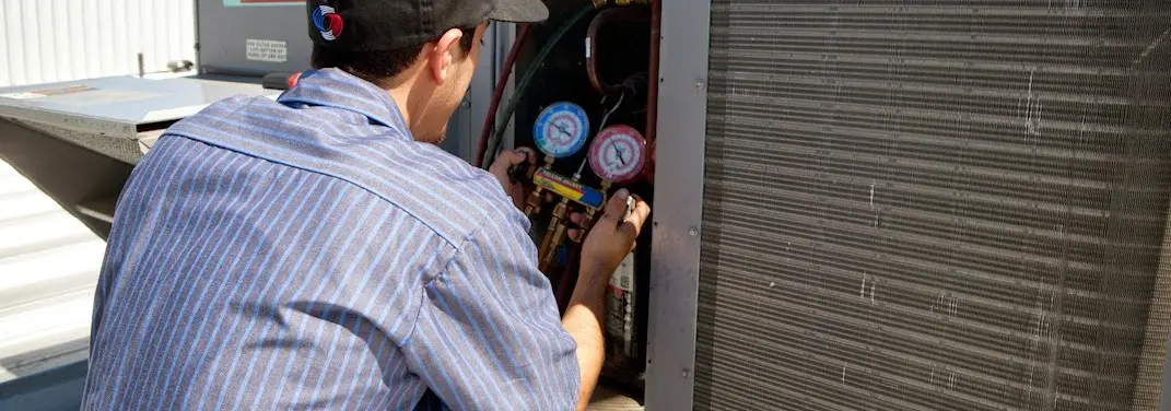 HVAC technician servicing a condenser unit in Clemmons
